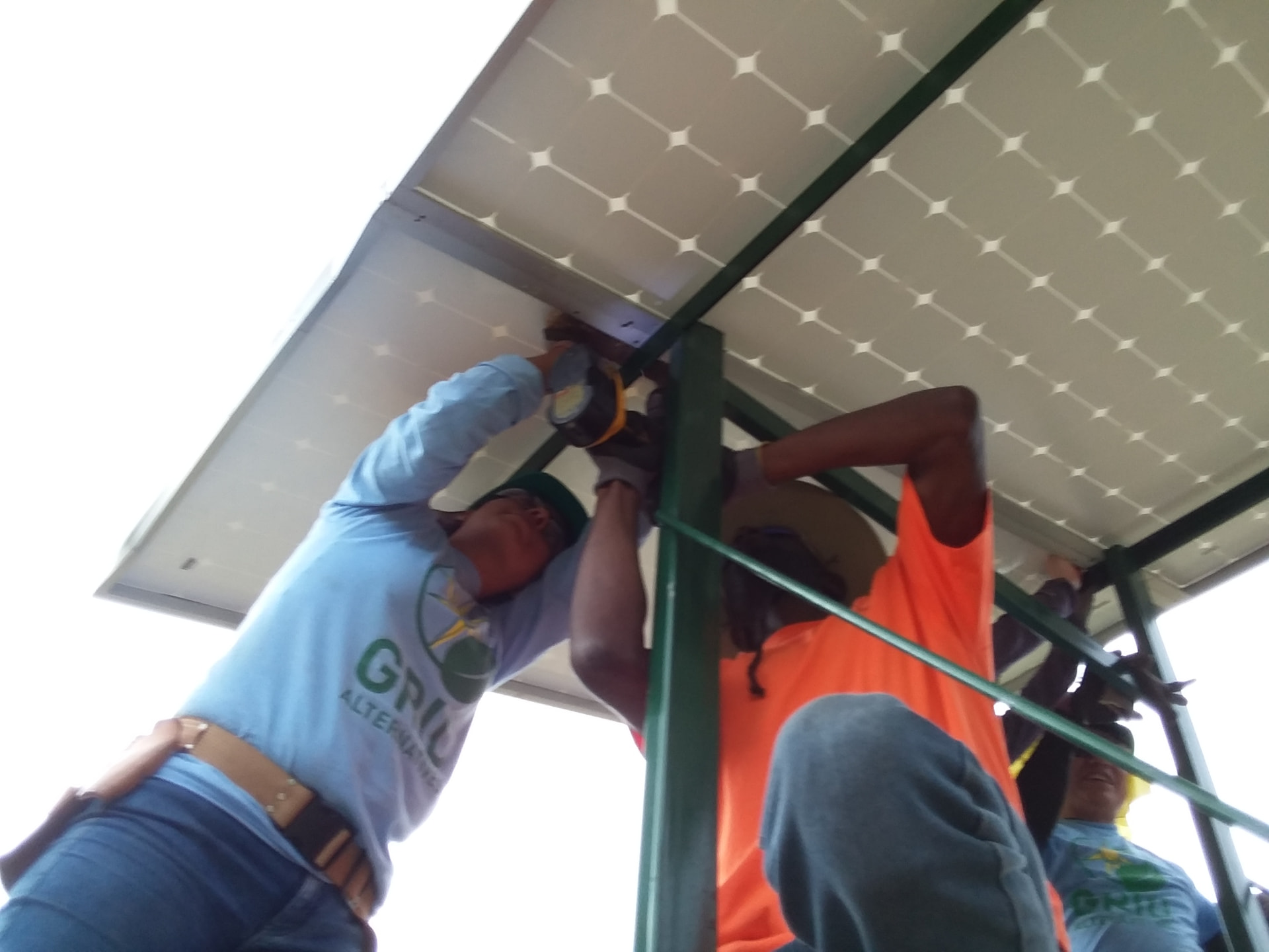 Team members working beneath solar panels during an installation