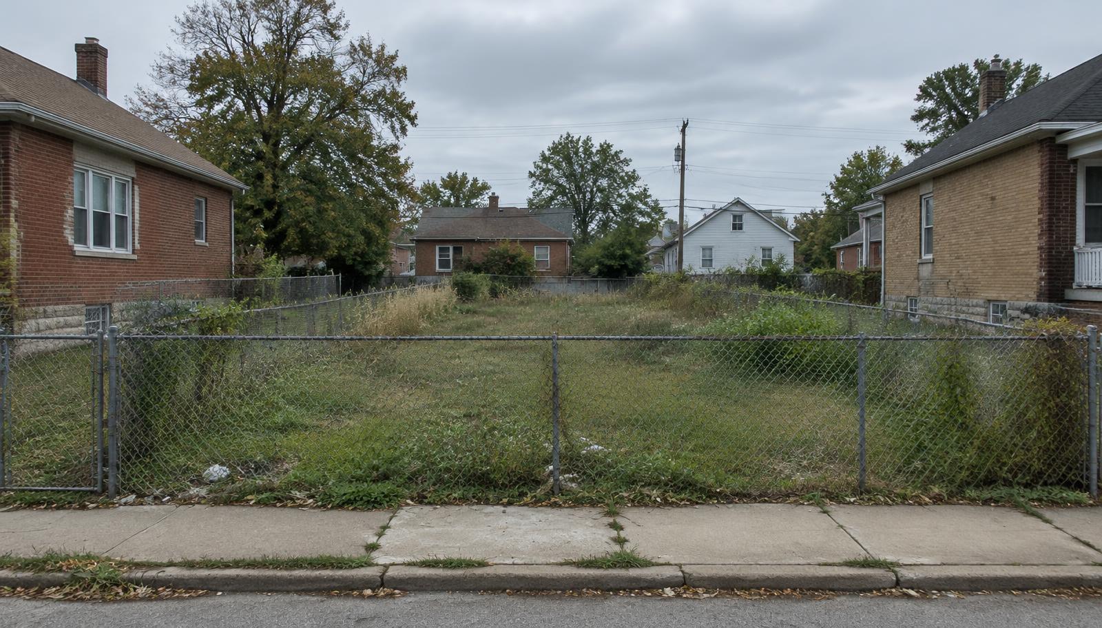 Illustrative vacant, overgrown lot between houses